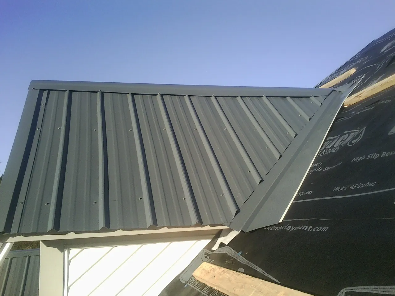 Gray metal roof panels going on over a garage gable in Cape Elizabeth