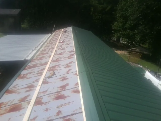 Old rusted panels beside newly installed green metal roofing — Wind Damage Roof Repair by Roofing Brothers in Cape Elizabeth
