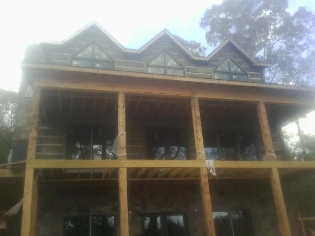 Dormers and porch framing on a large log home under construction — Roof Coating work by our crew in Cape Elizabeth