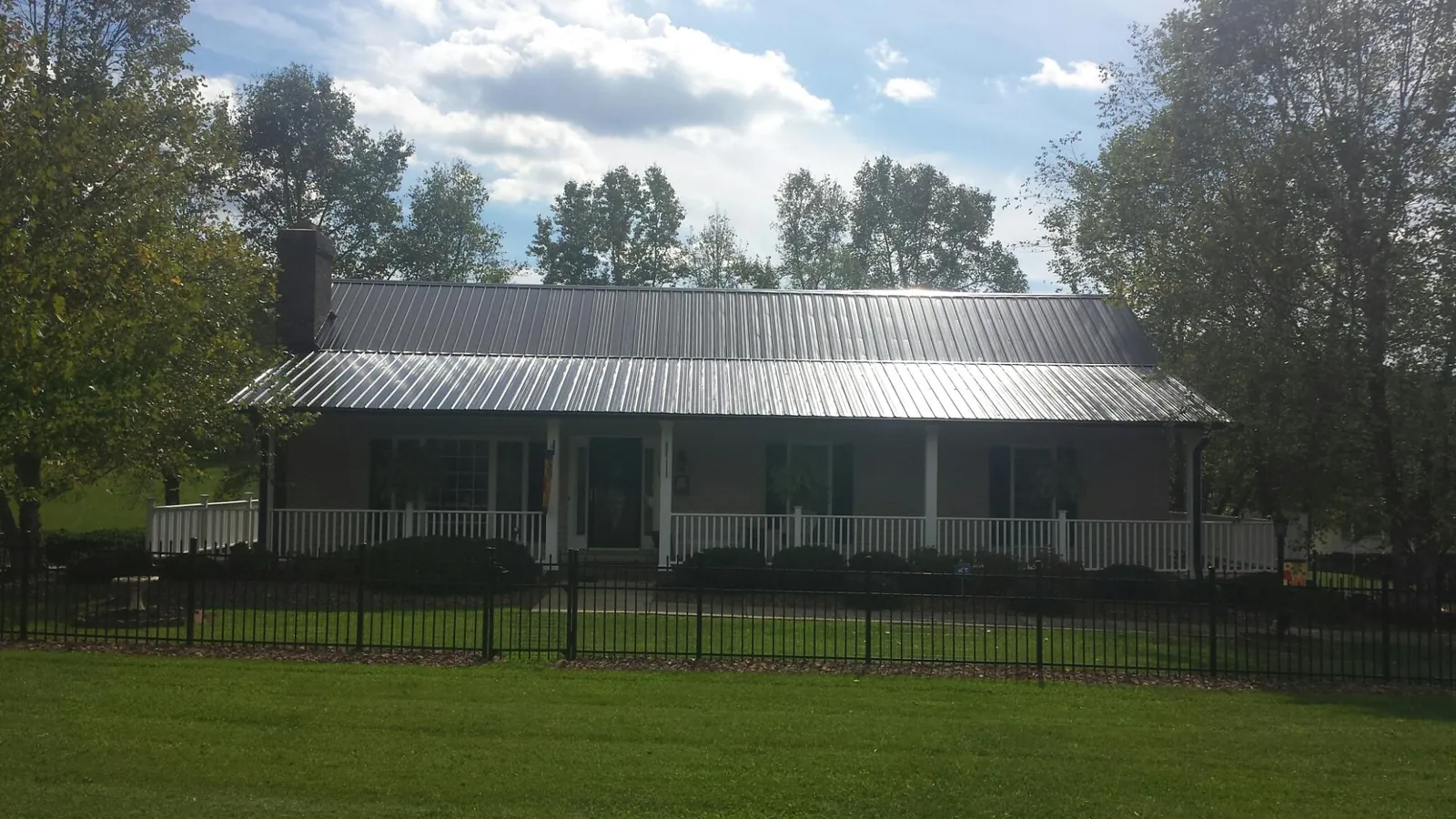 Gray metal roof on a brick ranch with a full width front porch — Gutter Guard Installation work by our crew in Cape Elizabeth