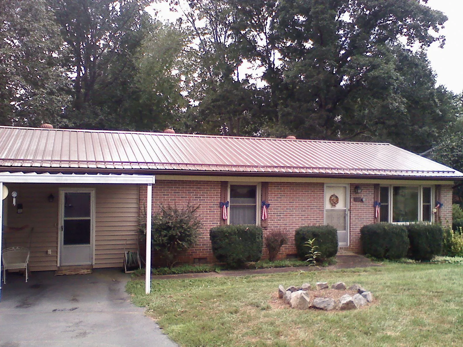 Bronze metal roof and carport on a brick ranch home — Roof Repair work by our crew in Cape Elizabeth