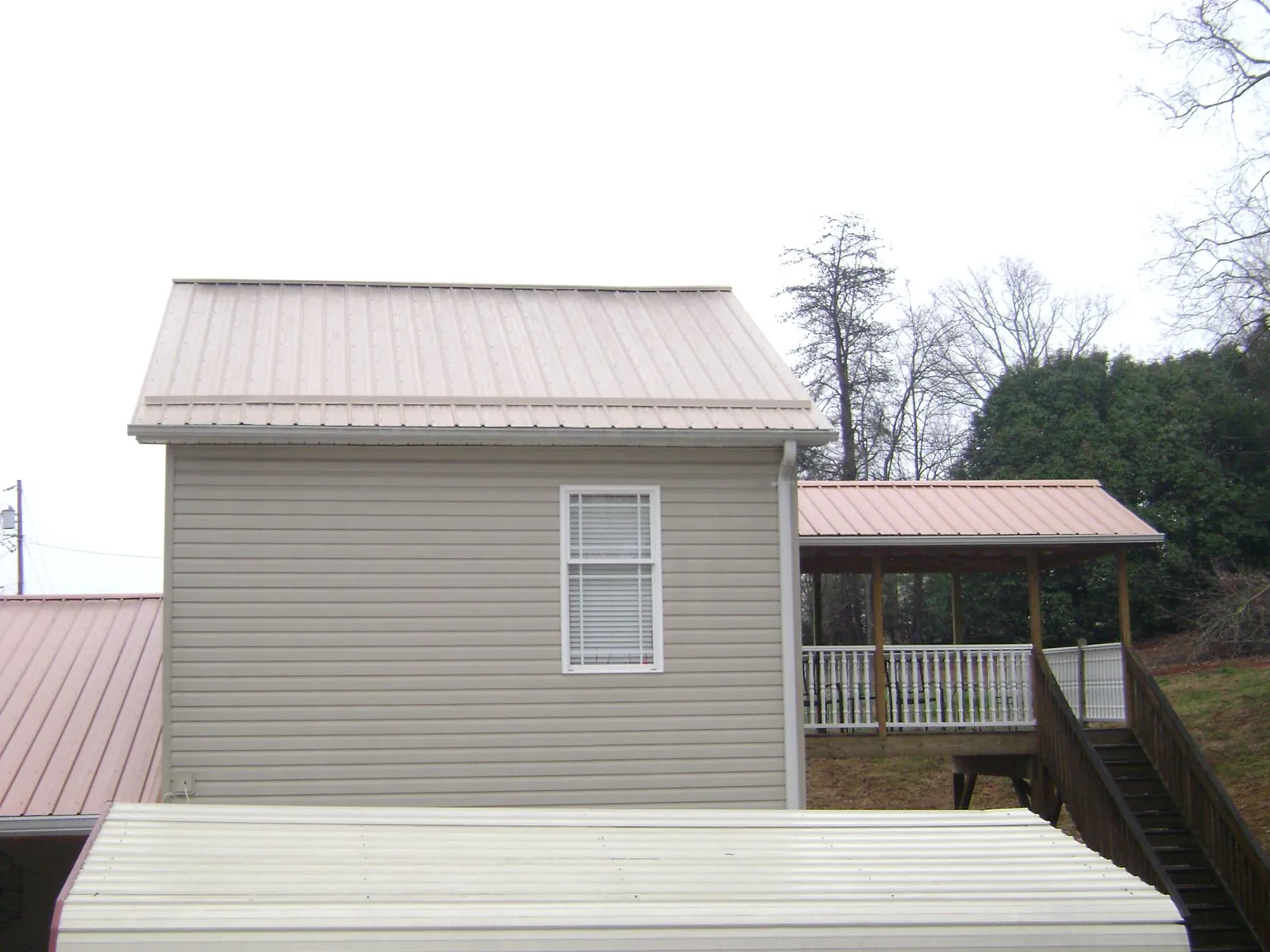 Tan metal roofs on a two story addition and attached porch, from a Roof Replacement job in Cape Elizabeth